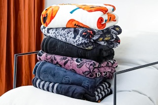 Lifestyle image of folded Way to Celebrate Halloween throw blankets on chair