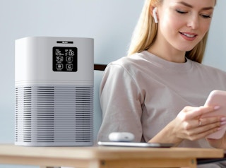 a woman sitting next to a air purifier on a table