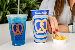 a person dipping a pretzel nugget into cheese at auntie annes