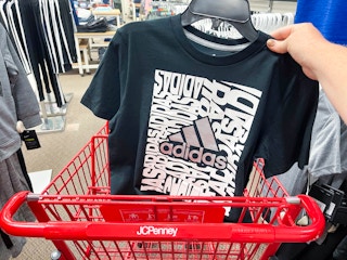 hand holding Adidas t-shirt in shopping cart
