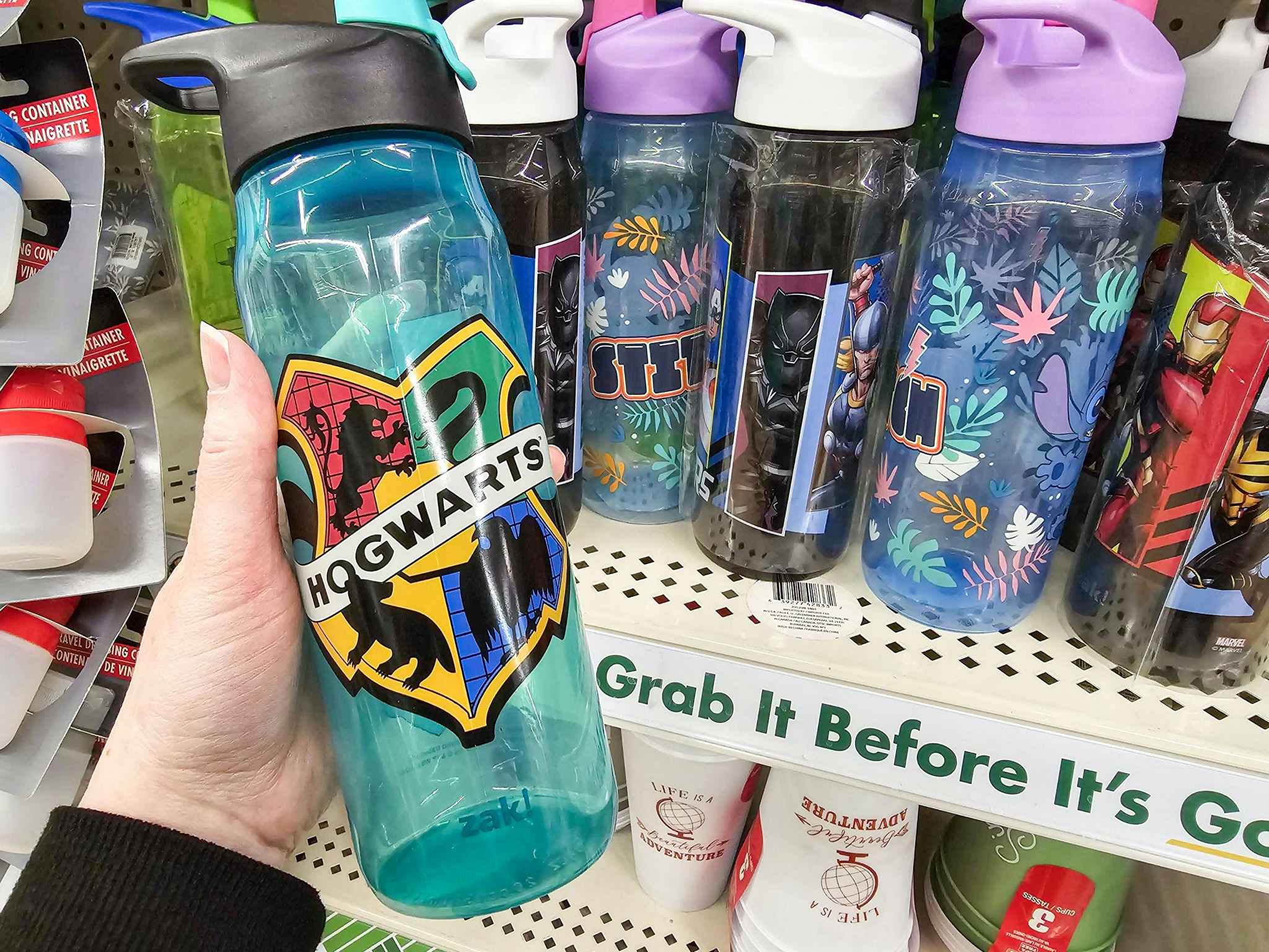 person holding a hogwarts water bottle in front of other licensed water bottles