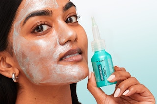 L'oreal exfoliant peel on women's face while she's holding the bottle