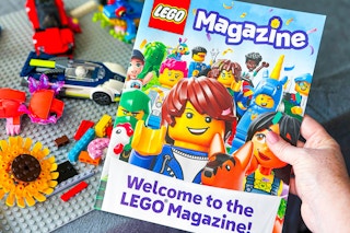 lego magazine being held by a table of legos 