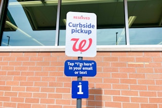 A curbside pickup sign outside of Walgreens that reads, "Reserved Curbside Pickup. Tap 'I'm here' in your email or text"