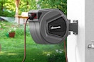 a retractable garden hose reel on a wall outside 