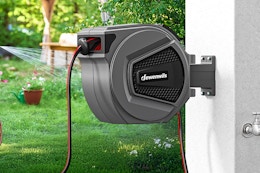 a retractable garden hose reel on a wall outside 