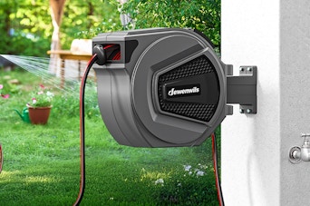 a retractable garden hose reel on a wall outside 
