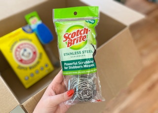 hand holding scotch brite stainless steel scrubbers in front of an amazon box