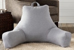 Lifestyle image of the Jumbo Cement Gray Polyester Best Rest Pillow on the floor near a chair