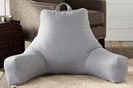 Lifestyle image of the Jumbo Cement Gray Polyester Best Rest Pillow on the floor near a chair
