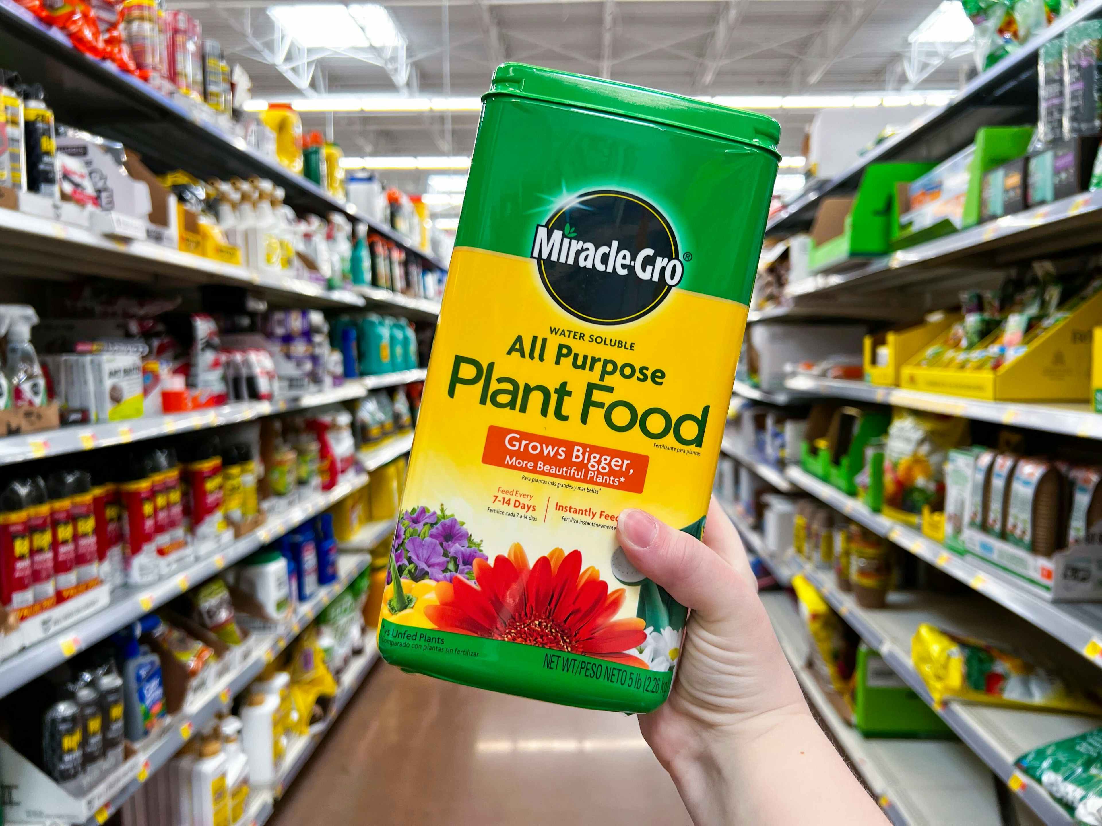 person holding miracle gro plant food in an aisle