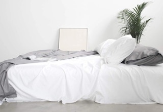 A set of white sheets on an unmade bed
