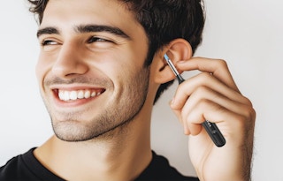 a person cleaning their ear with an earwax tool