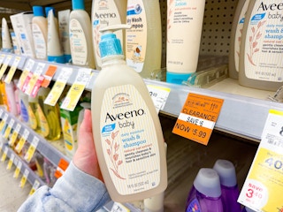 person holding a bottle of aveeno baby shampoo by a $5.99 clearance sign