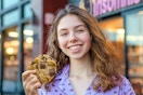 a woman in pajamas holding a cookie from insomnia cookies