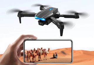 black camera drone with someone holding a phone to watch