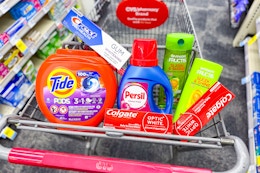 tide pods, crest and colgate toothpaste, persil detergent, and garnier shampoo in a cart