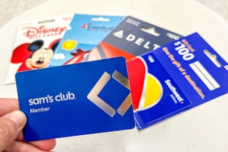 a person holding up a sams club gift card in front of various travel gift cards