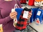 A person standing in Old Navy, holding some pairs of cozy socks.