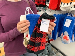 A person standing in Old Navy, holding some pairs of cozy socks.