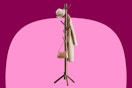 A brown coat tree with 8 hooks and a tan trench coat and hat and brown purse hanging on it