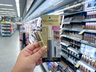 hand holding l'oreal mascara and lipstick in walgreens