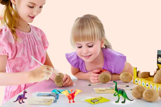 Lifestyle image of a Dinosaur Egg Excavation Kit at Walmart (2 girls playing with it)