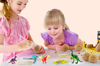 Lifestyle image of a Dinosaur Egg Excavation Kit at Walmart (2 girls playing with it)