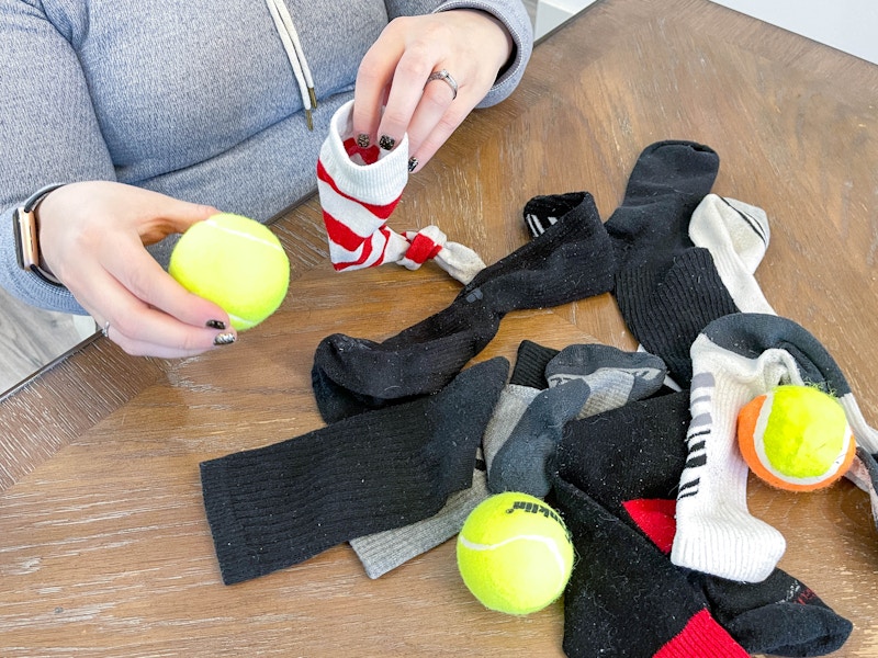 a person putting a tennis ball into a sock