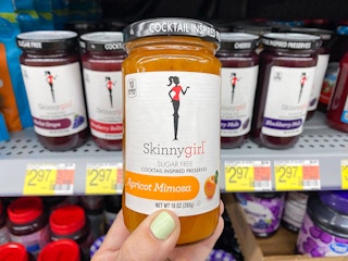 person holding a jar of skinnygirl brand preserves in front of a shelf
