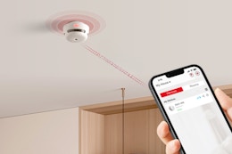 a smoke detector on a ceiling being controlled by a smartphone 