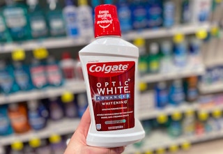 hand holding a bottle of Colgate Optic White mouthwash