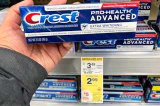 a hand holding a box of crest pro healthy advanced toothpaste at the drug store
