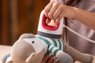 a girl using a cricut press on a stuffed animal