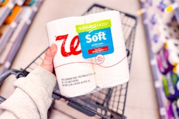 person holding a pack of toilet paper over a cart