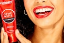 a woman smiling and holding a red tube of toothpaste