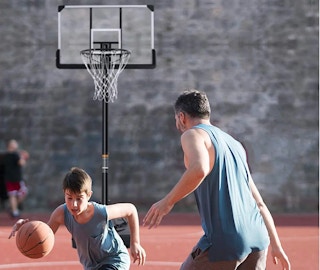 son and father playing basketball with the basketball hoop in the background