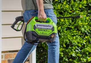 person carrying a greenworks pressure washer