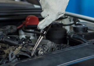 a person fixing a car with a magnetic flashlight tool