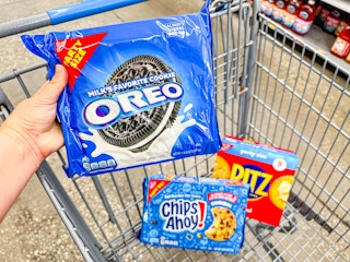 hand holding oreos with ritz and chips ahoy in walmart cart