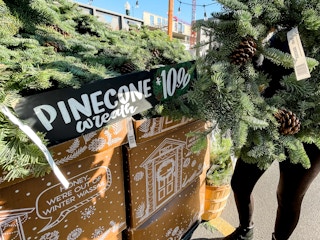 person holding pinecone wreath for $10.99 at trader joes