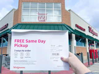 hand holding walgreens photo order in front of walgreens store