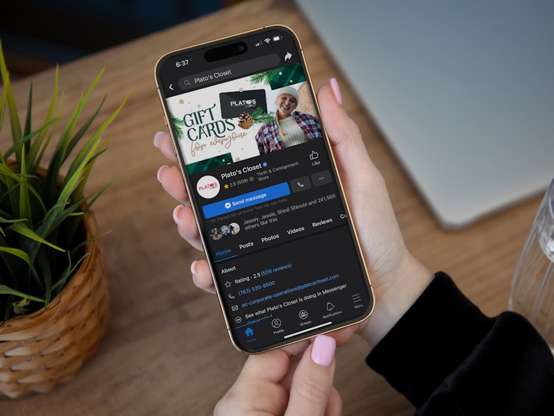 Someone using their phone to look at the Plato's Closet Facebook page