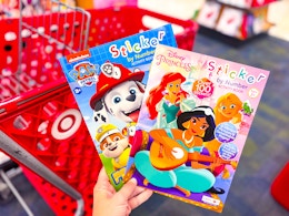 hand holding 2 coloring books in front of a target cart