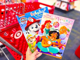 hand holding 2 coloring books in front of a target cart