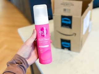 hand holding eos shea better shave cream in front of an amazon box