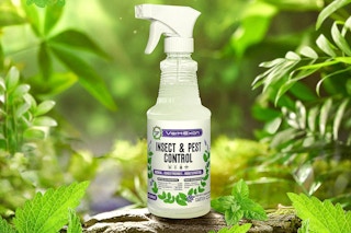 A green leafy area where a bottle of peppermint insect and pest control spray sits on a log