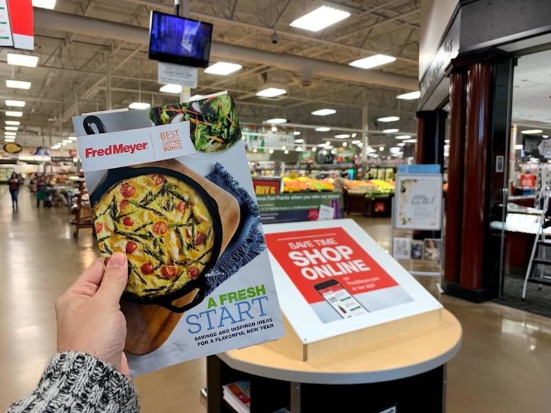 A person holding Fredmeyer best customer bonus coupon mailer.