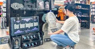 a person shopping in spirit halloween and picking up a haunted mansion tomb stone