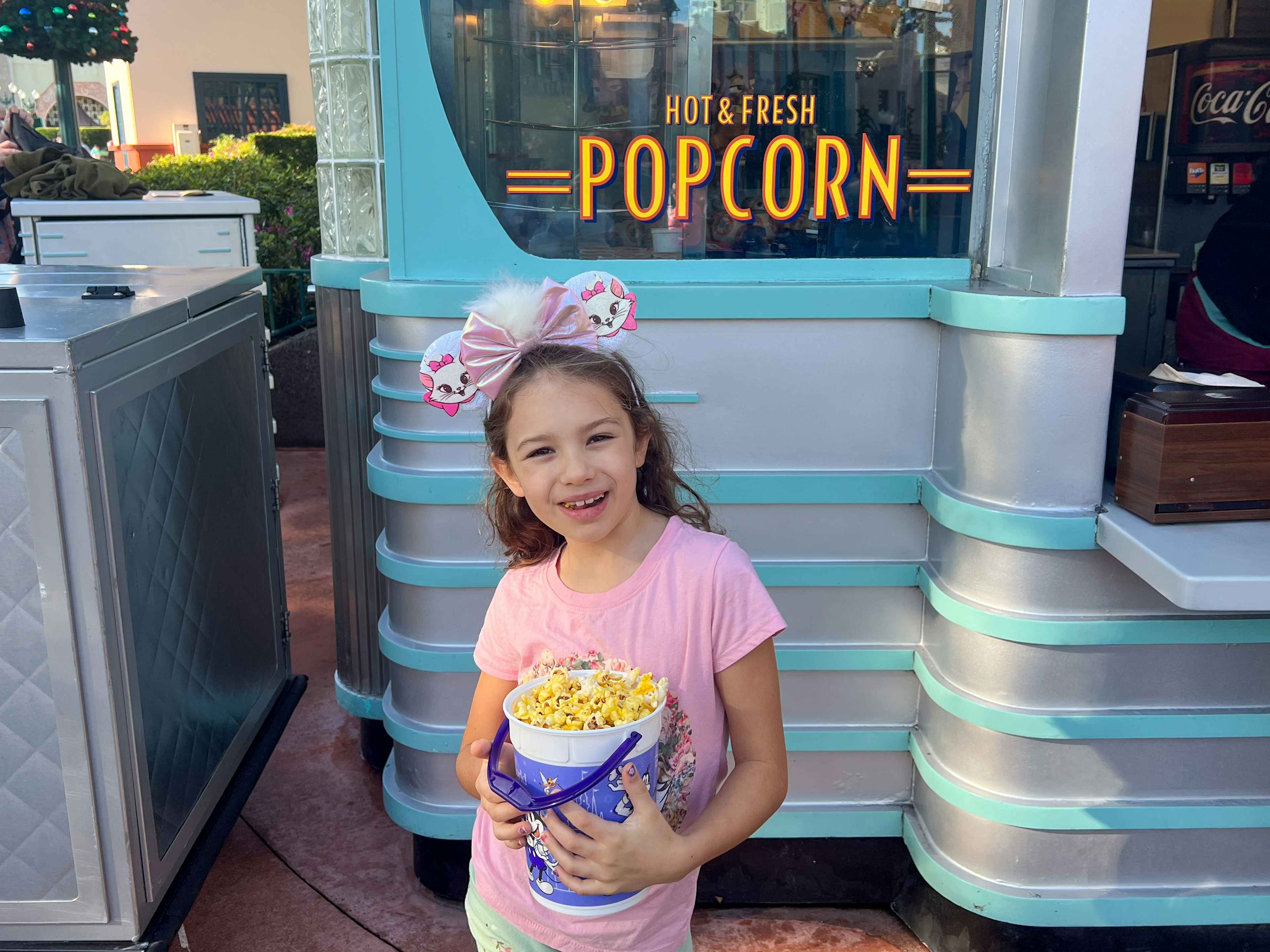 a child with mouse ears holding a popcorn bucket at Disney World